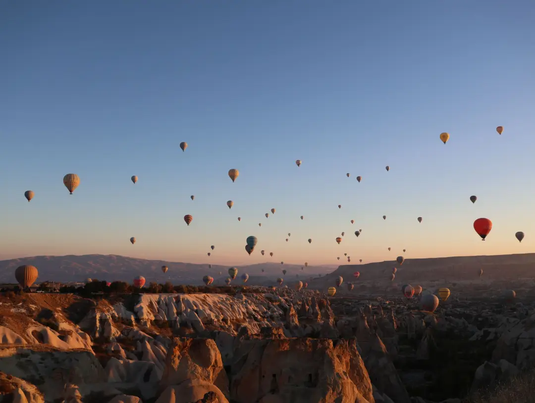 Gün doğumunda Göreme'deki peri bacalarının üzerinde süzülen sıcak hava balonları